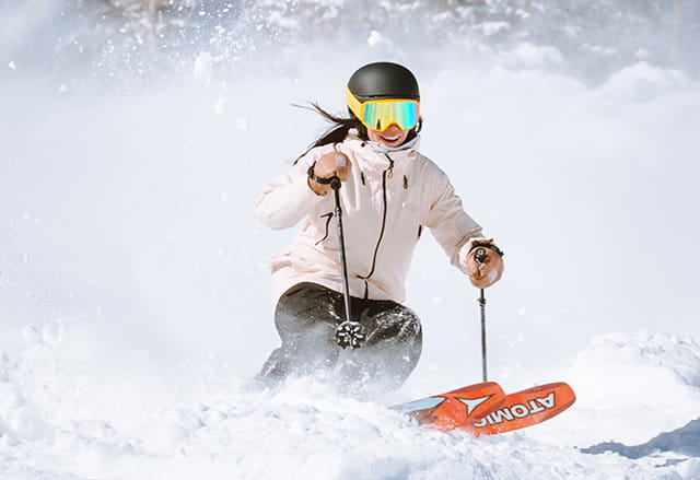 A female skier enjoying pure powder with her Ikon Pass