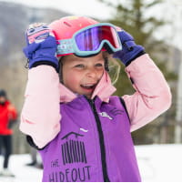 Girl in purple and pink ski wear smiling on a ski slope