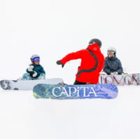 Snowboard instructor giving a lesson to two young snowboarders