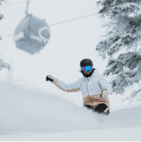 snowboarder in knee deep powder under the aspen gondola, on a snowy day