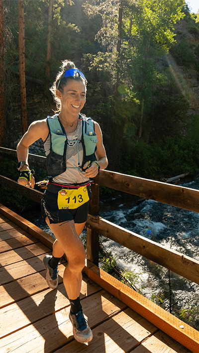 Runner competes in Power of Four Run, she smiles as she runs across a bridge