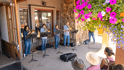 Bluegrass Band plays in front of a crowd on a summer day on top of Aspen Mountain, at the Sundeck