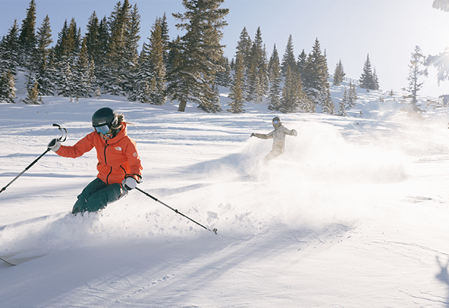 Two skiers in powder at Aspen Snowmass, on a bluebird day. 