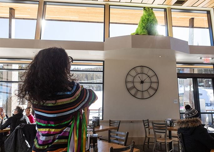 Paula Pivi bear exhibit in the Aspen Mountain lodge, artist looks up at her green feather polar bear