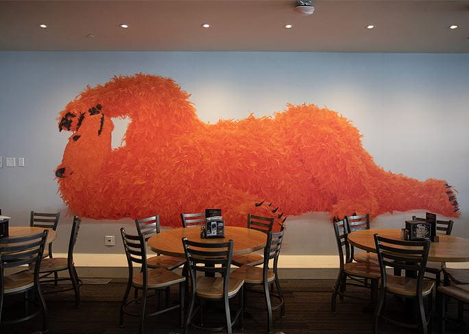 Image of Paula Pivi's orange feather polar bear printed on the Aspen Snowmass dining walll