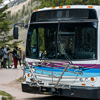 Close up of the RFTA bus at maroon bells, bus is white with retro blue and purple stripes 