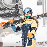 Person in yellow ski jacket under the Snowmass gondola on a snowy day