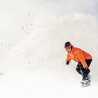 snowboarder rides down powdery slope, as snow blows up behind them, a Aspen Snowmass