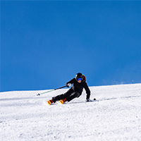 single skier carves into a turn on a groomer on a bluebird day at Aspen Snowmass