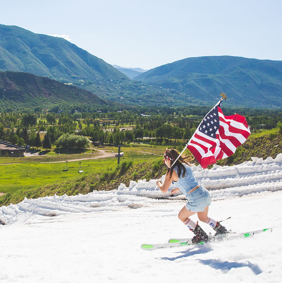 Woman skiing Buttermilk's last snow with an American flag