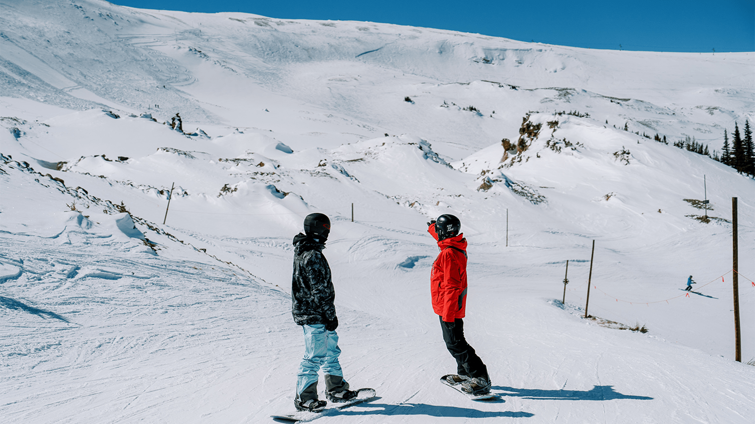 A snowboard pro at Aspen Snowmass instructs a guest as they approach steep terrain