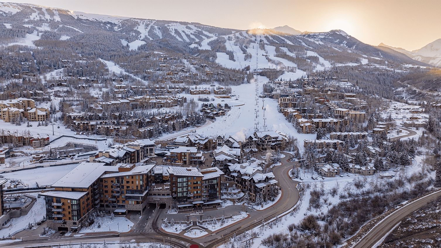 long view of Snowmass, Limelight hotel at base and expansive resort in background, at sunrise