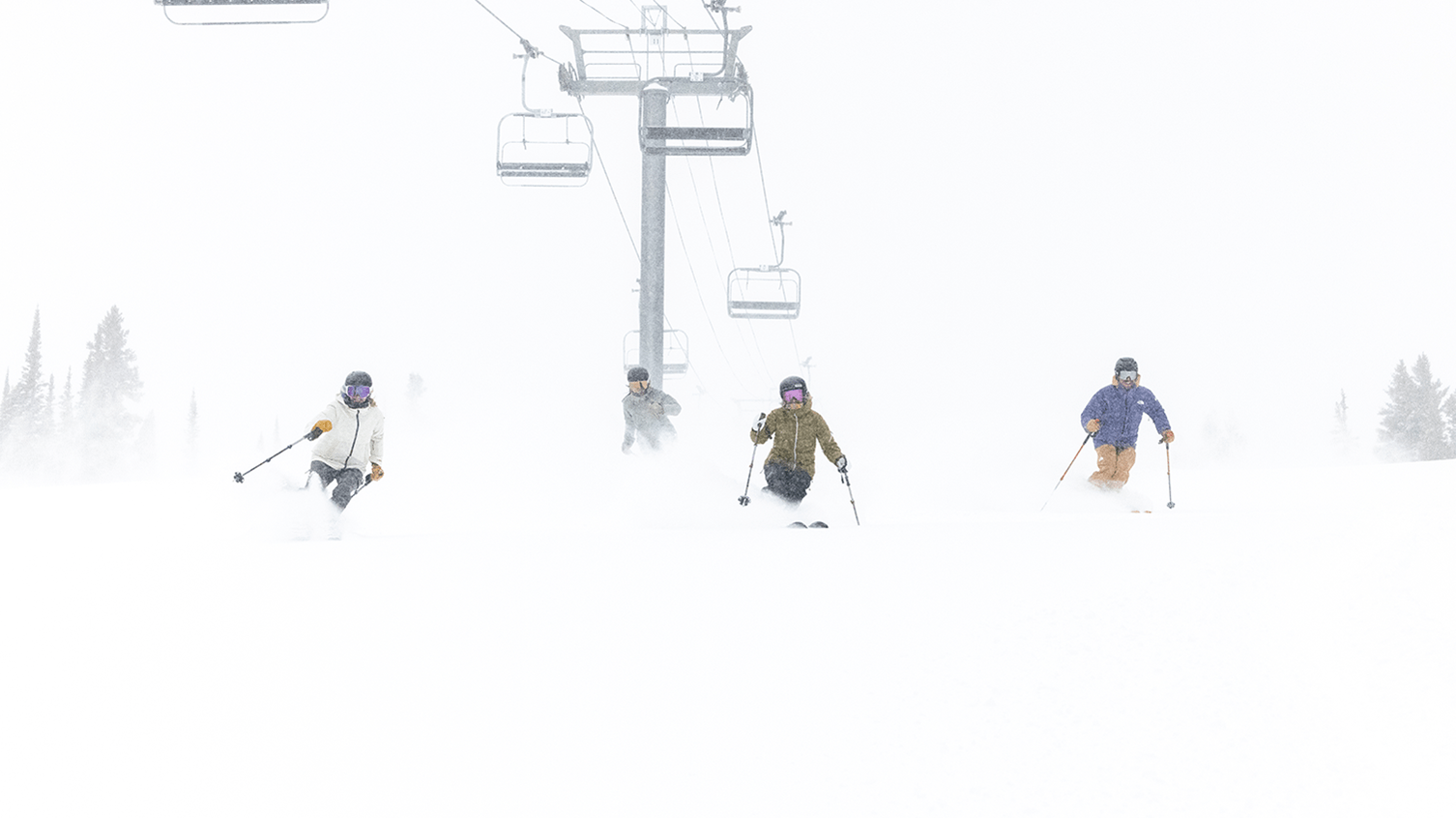 Four skiers under the big burn lift at Aspen Snowmass, cloudy day with deep powder