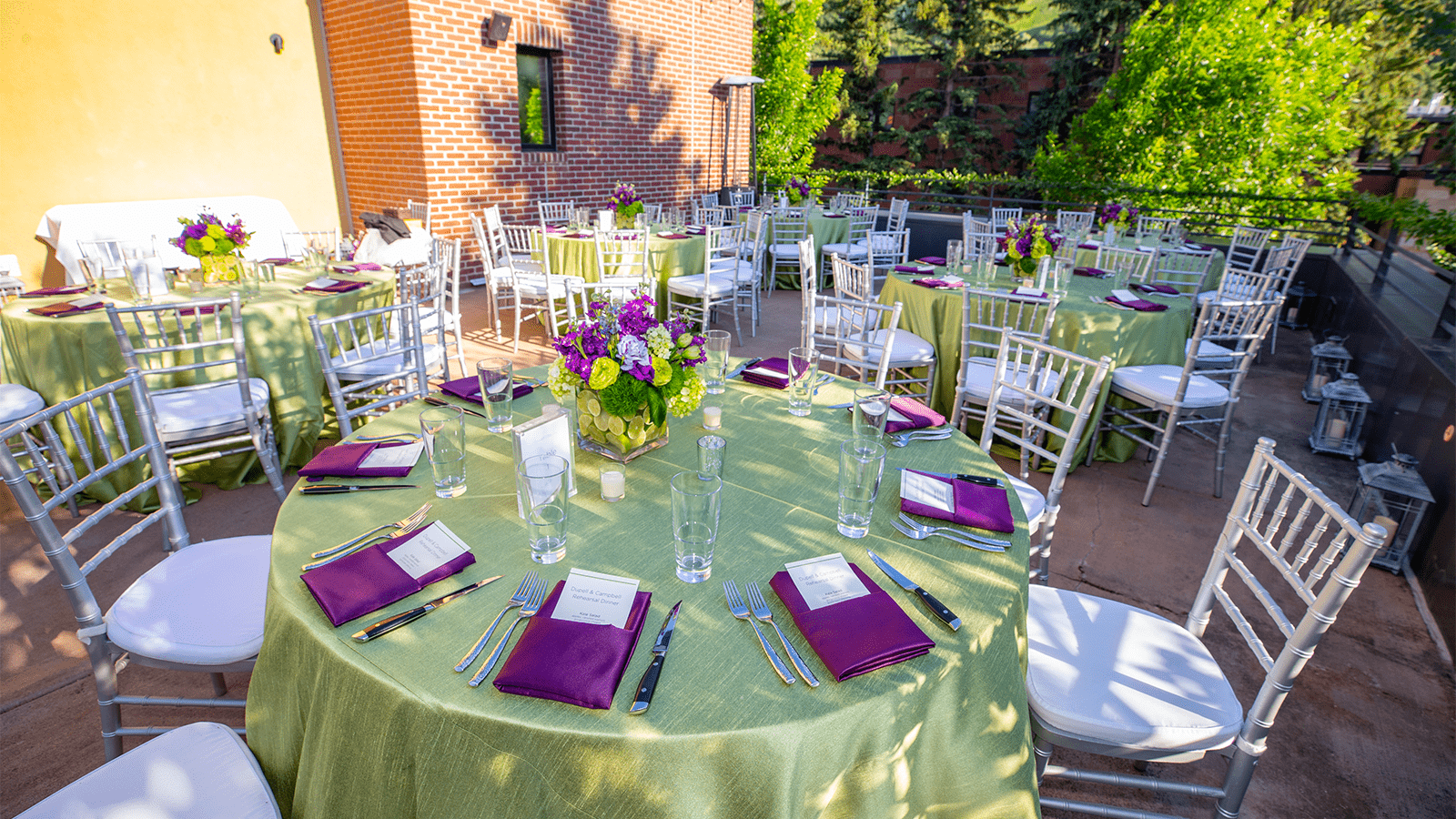 Reception dinner, green table cloth over circular tables in the shade on a wedding venue