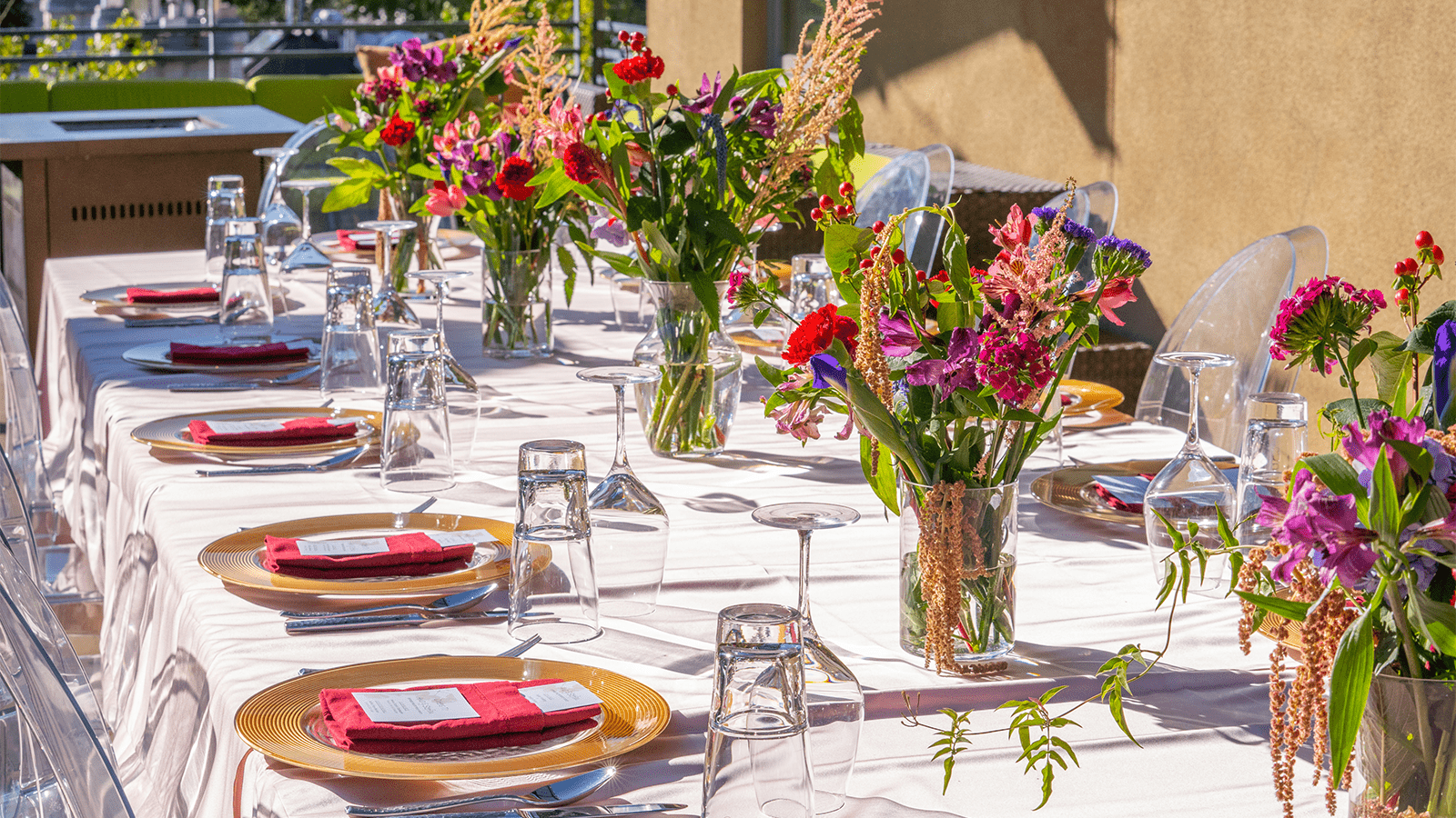 a beautiful wedding table is set up on a white table cloth, colorful flowers line the table during golden hour