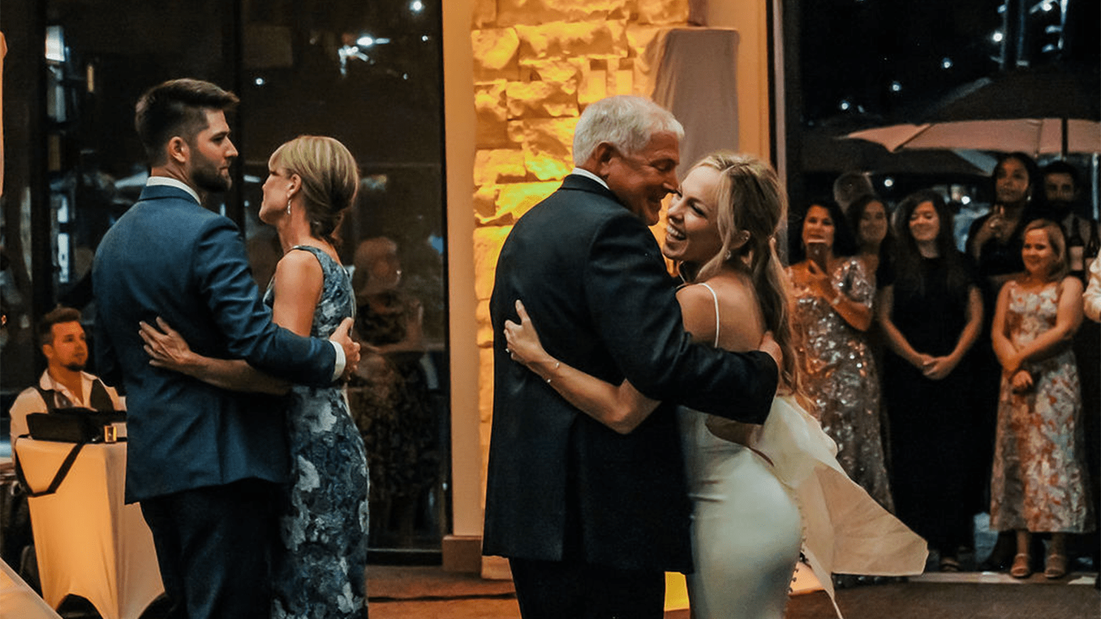 Bride and father dance under dimmed lighting in front of guests