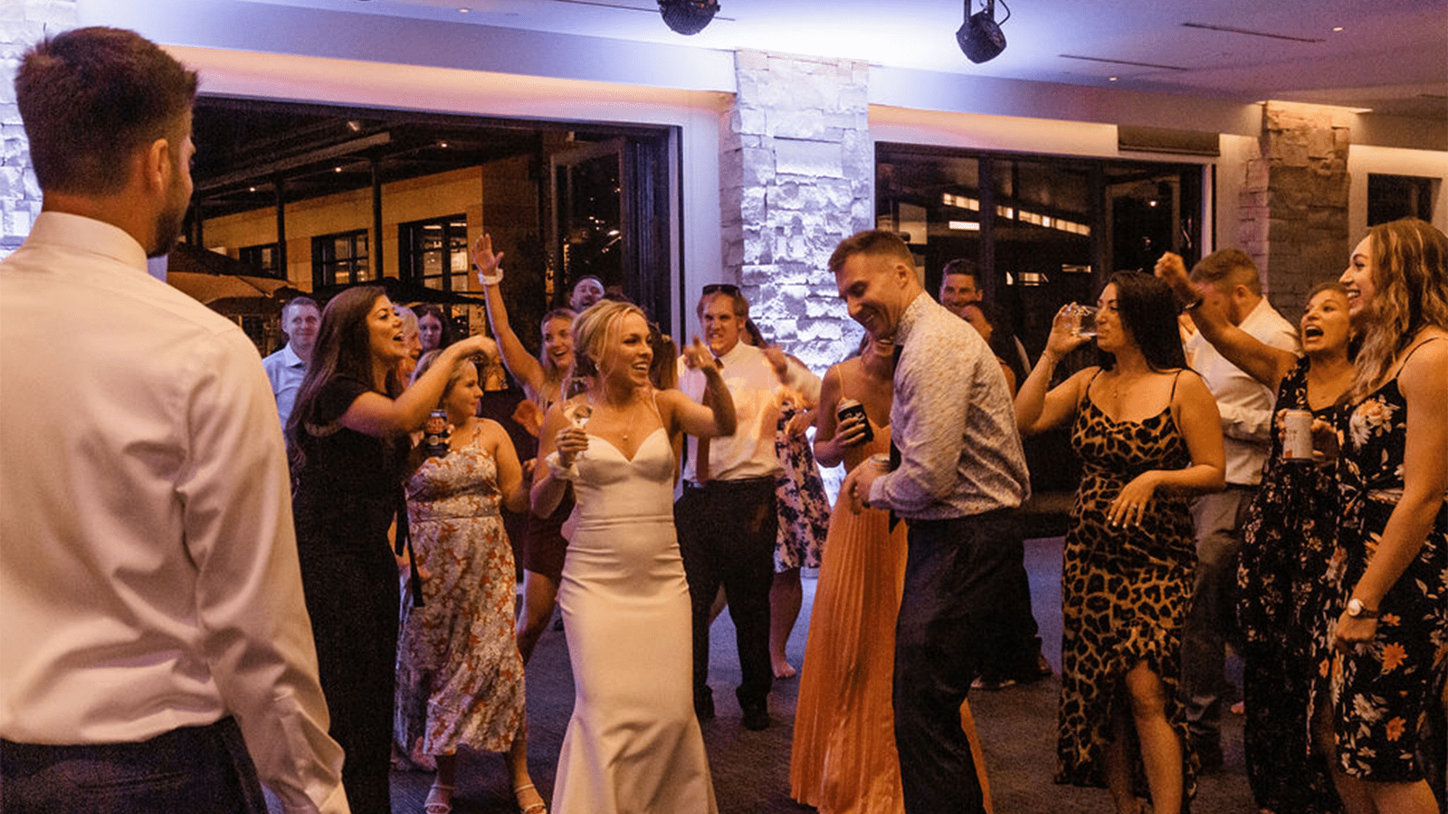 Guests dance around bride on dance floor, purple lighting sets the mood