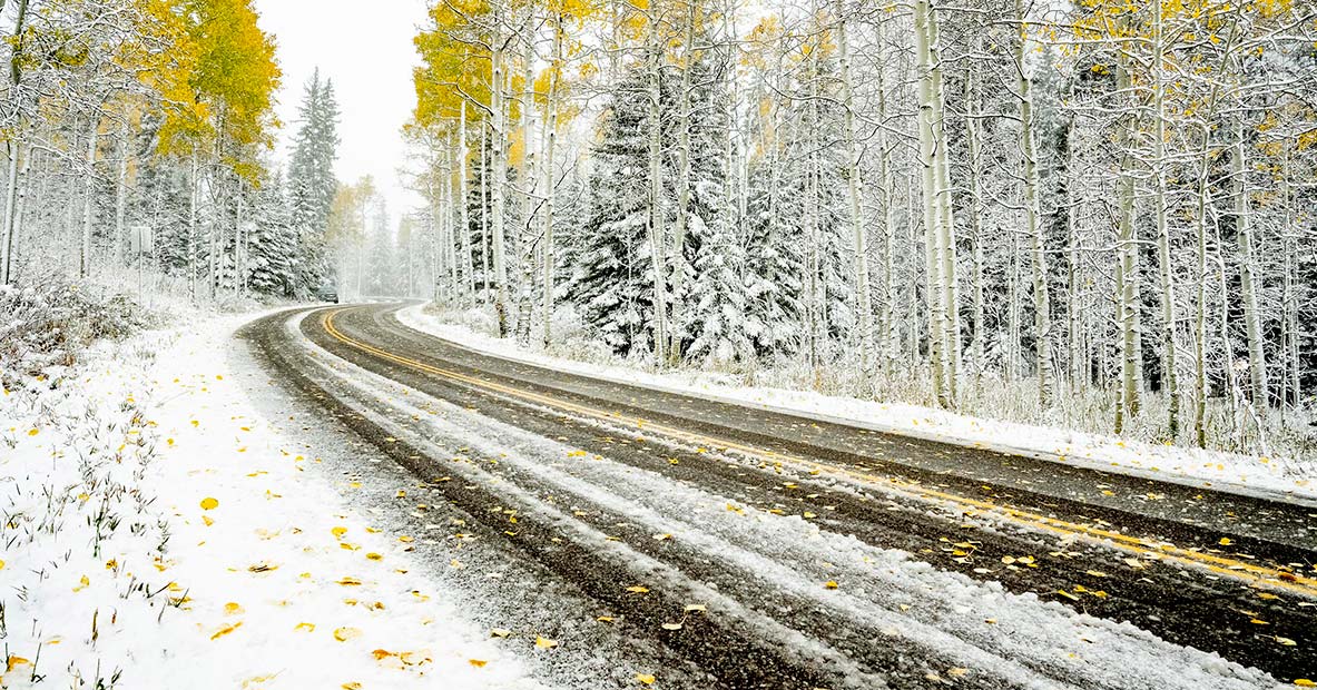 Aspen road in autumn with first snow fall