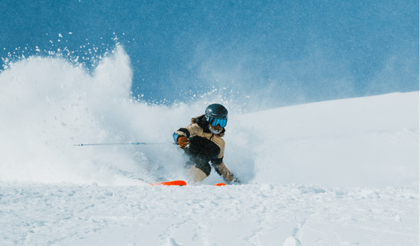 Skier on Aspen highlands on bluebird day in deep powder
