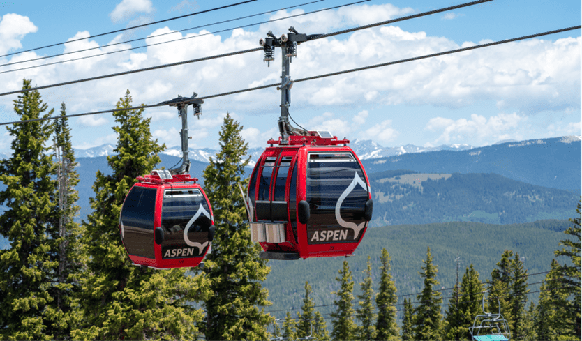 red gondolas on aspen mountain as they travel up towards the peak during summer