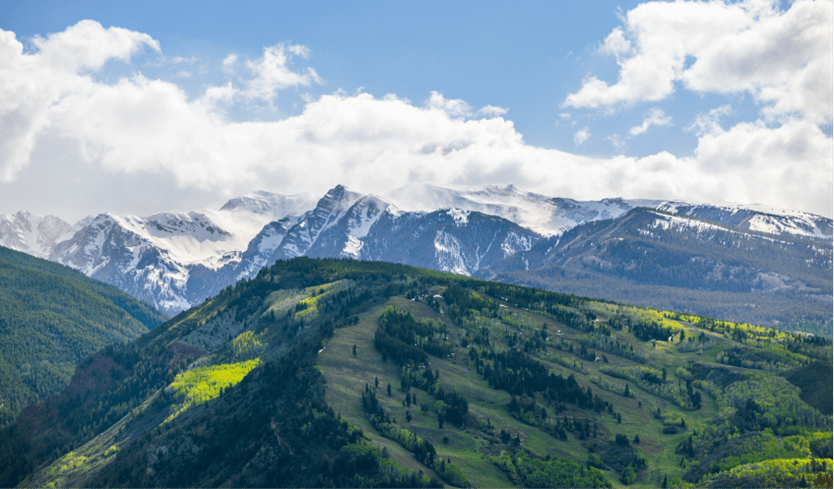 Green summer ski runs of Buttermilk, under white fluffy summer clouds